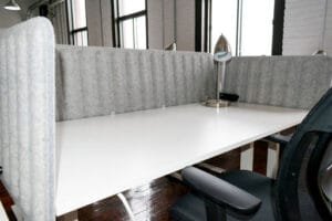 Petit bureau assis-debout chez Nuage B avec cloison grise et chaise ergonomique dans un espace lumineux.