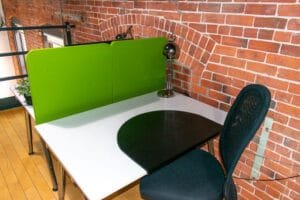Petit bureau fixe avec cloison verte, lampe de travail et mur de briques apparentes chez Nuage B.