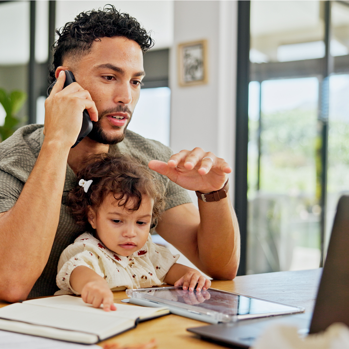 Professionnel en télétravail avec un jeune enfant à la maison, illustrant les distractions pouvant affecter la productivité pendant l'été.